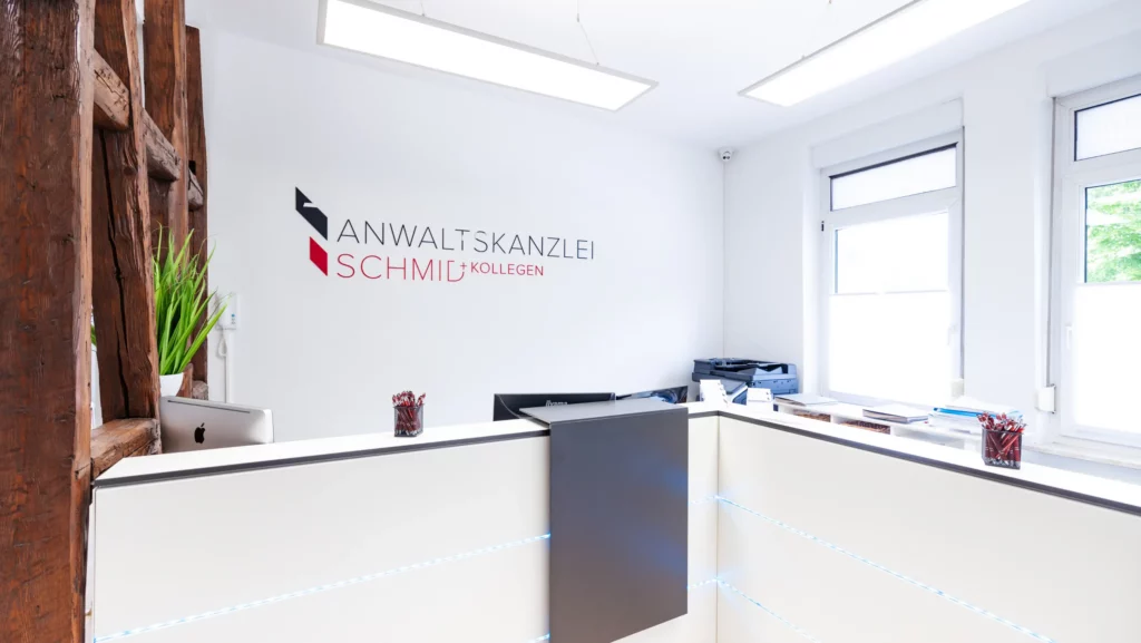 Empfangsbereich der Anwaltskanzlei Schmid + Kollegen mit Kanzleilogo an der Wand